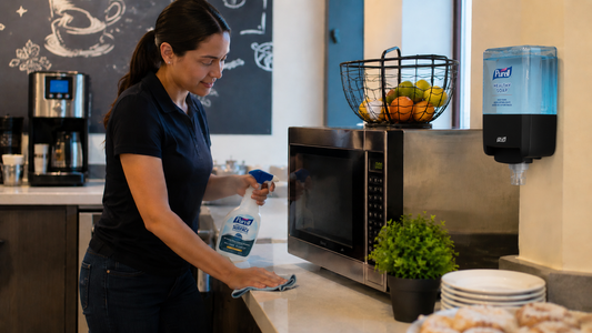 Personal de limpieza desinfectando superficies en un coffee point corporativo con PURELL Surface y sistema PURELL Healthy Soap para mejorar la inocuidad alimentaria.